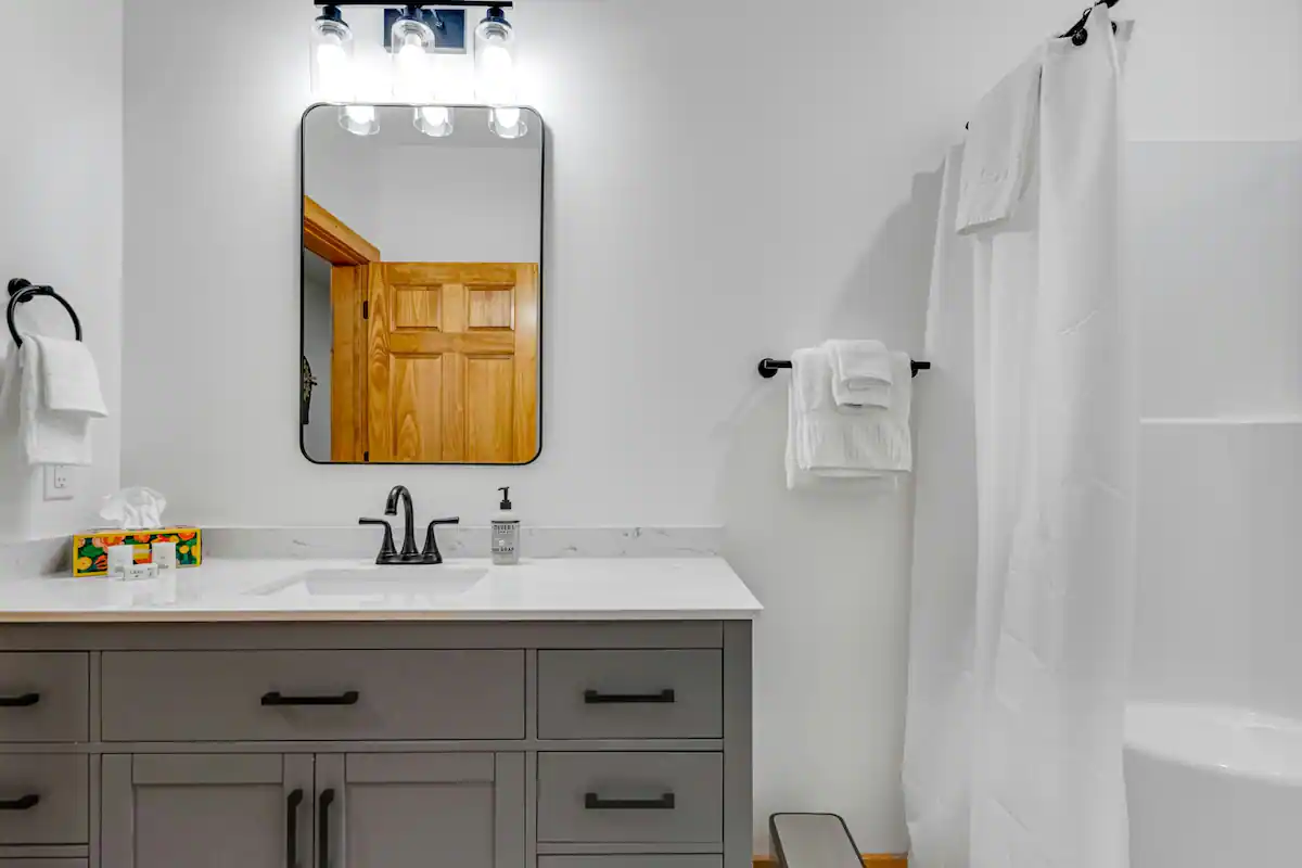 Bathroom with light fixtures, modern sink and cabinet, and shower