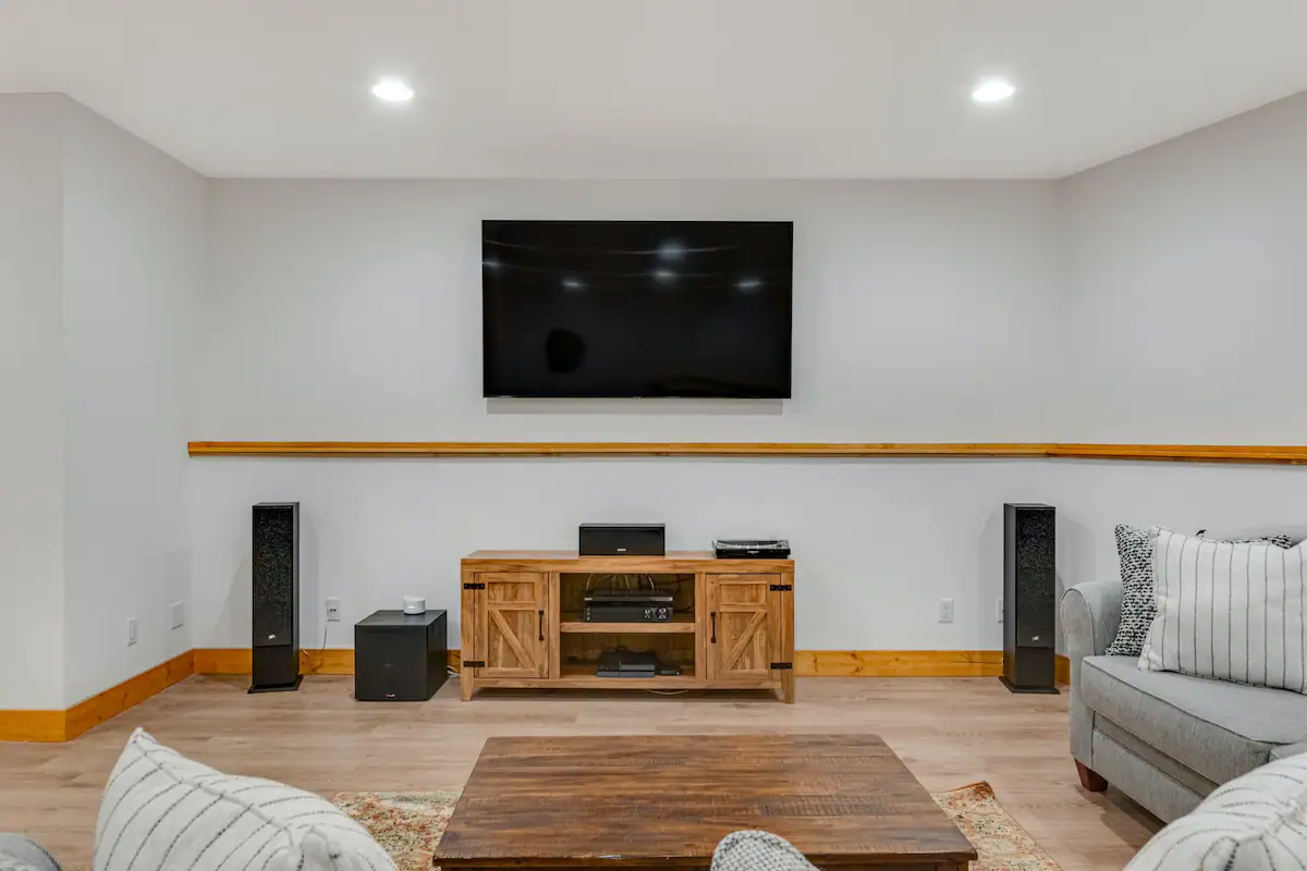 Living room with wooden floors, wooden tv stand, widescreen TV, and surround sound