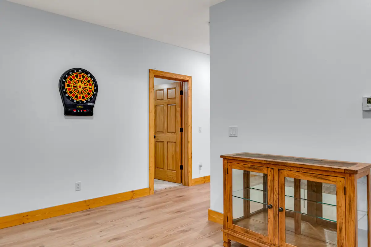 Interior view of house with a dart board, wood floors, and glass cabinet